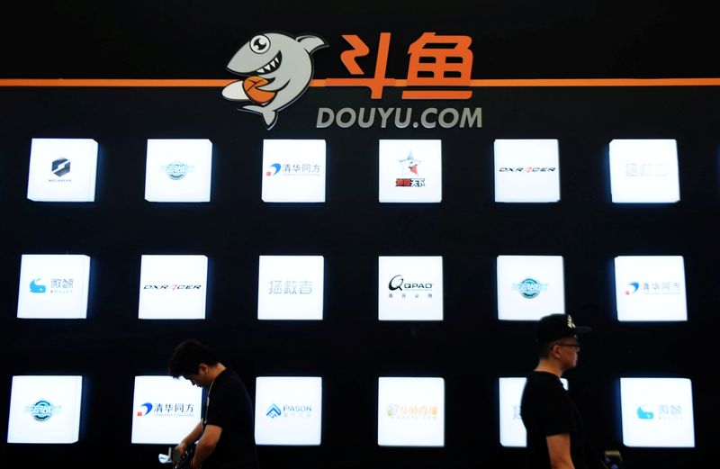 FILE PHOTO: People walk past a booth of live-streaming platform Douyu at the ChinaJoy digital entertainment expo in Shanghai