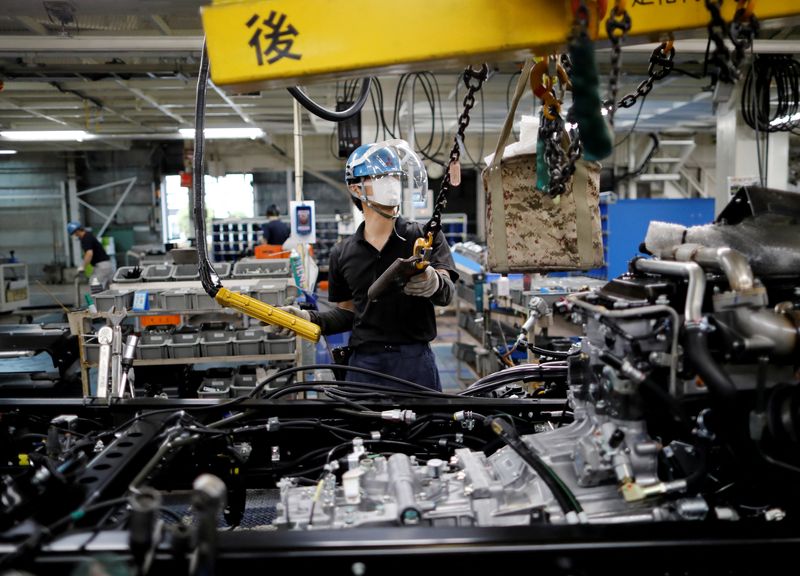 FILE PHOTO: An employee wearing a protective face mask and face guard works on the automobile assembly line at the factory of Mitsubishi Fuso Truck and Bus Corp in Kawasaki