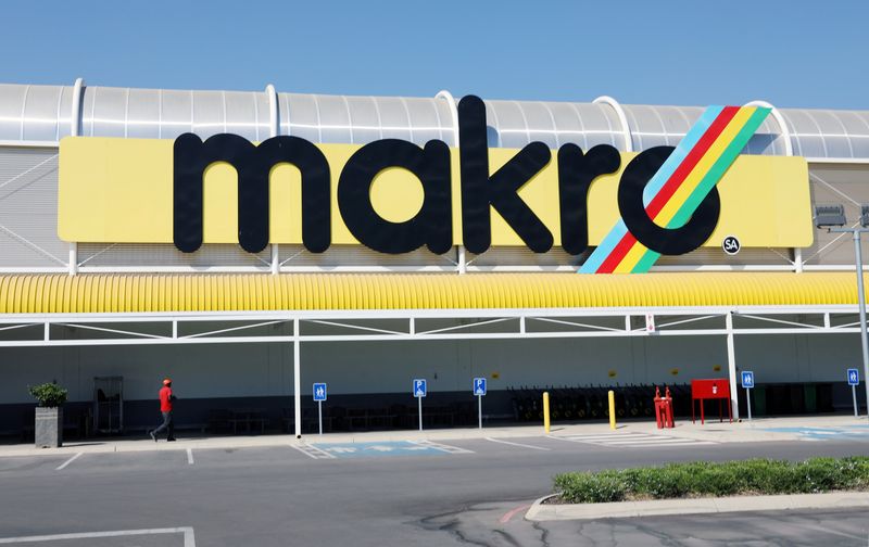 A worker walks beneath a logo at Makro Store Riversands of South African retailer Massmart in Midrand