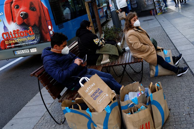 People sit next to shopping bags during winter sales in Madrid