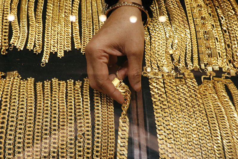 A vendor arranges gold chains displayed at VJ Gold and Diamond jewellery shop in Kuala Lumpur