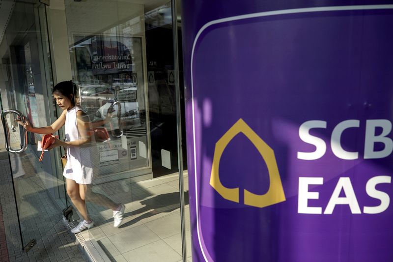 FILE PHOTO: A woman walks out from a Siam Commercial Bank branch in Bangkok