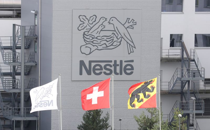 FILE PHOTO: Swiss national flag flies beside a flag of the canton of Bern in front of the logo of Nestle in Konolfingen