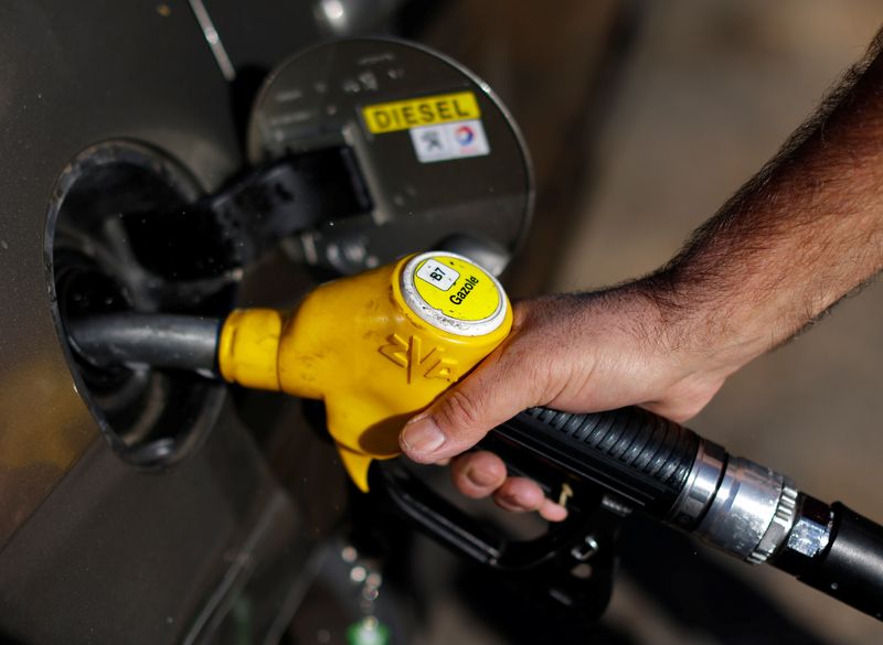 An employee holds a diesel fuel nozzle at a petrol station in Nice
