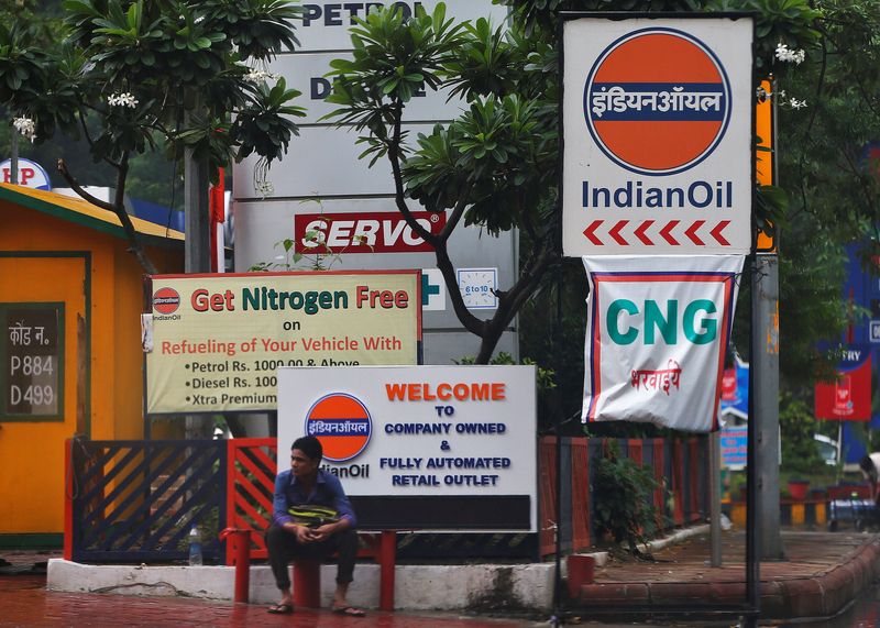 A man sits outside an Indian Oil fuel station in New Delhi