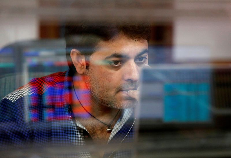 FILE PHOTO: A broker reacts while trading at his computer terminal at a stock brokerage firm in Mumbai