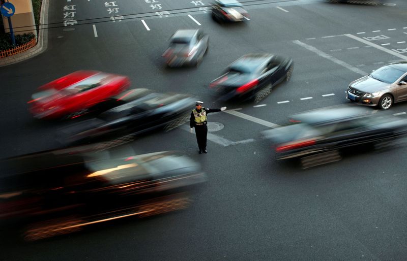 FILE PHOTO: A policeman directs traffic at a busy street of downtown Shanghai