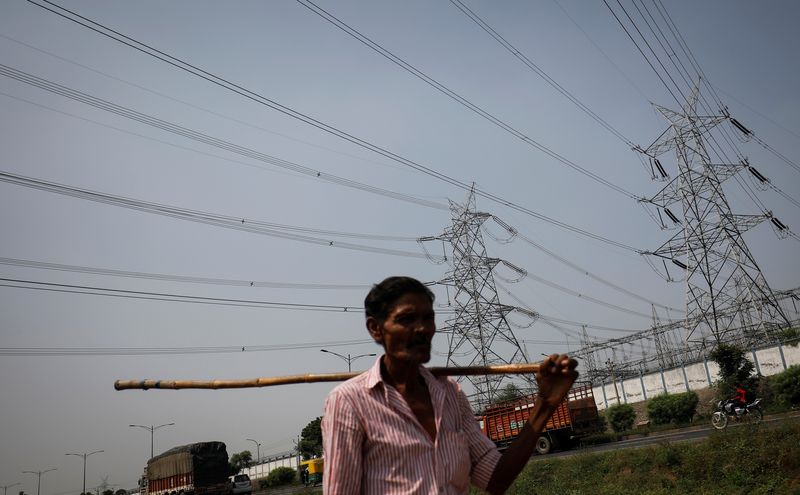 FILE PHOTO: Man walks past electricity pylons on the outskirts of Ahmedabad