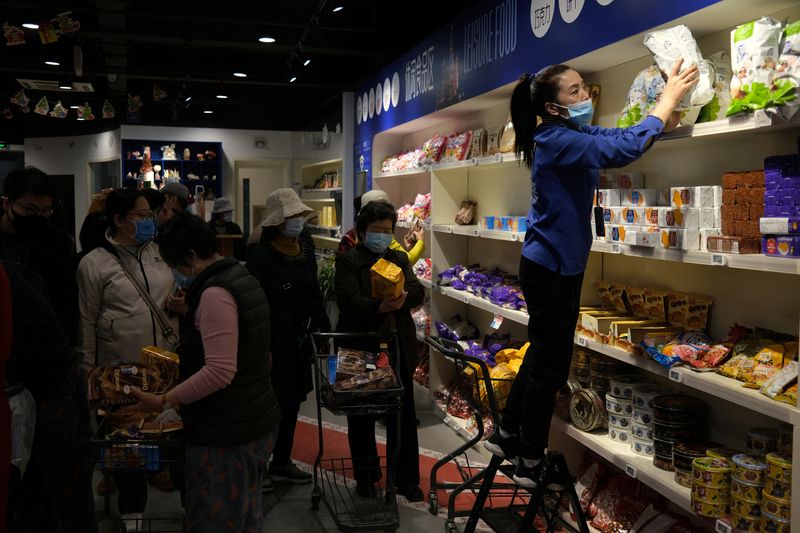 Staff member sorts snacks as customers shop at a supermarket featuring Russian goods in Beijing