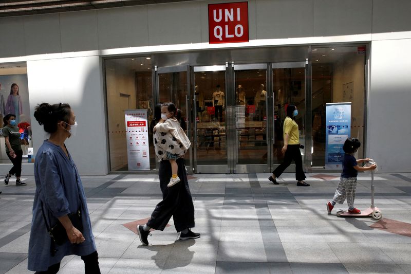 FILE PHOTO: People wearing face masks walk past a store of Fast Retailing's fashion chain Uniqlo in Beijing