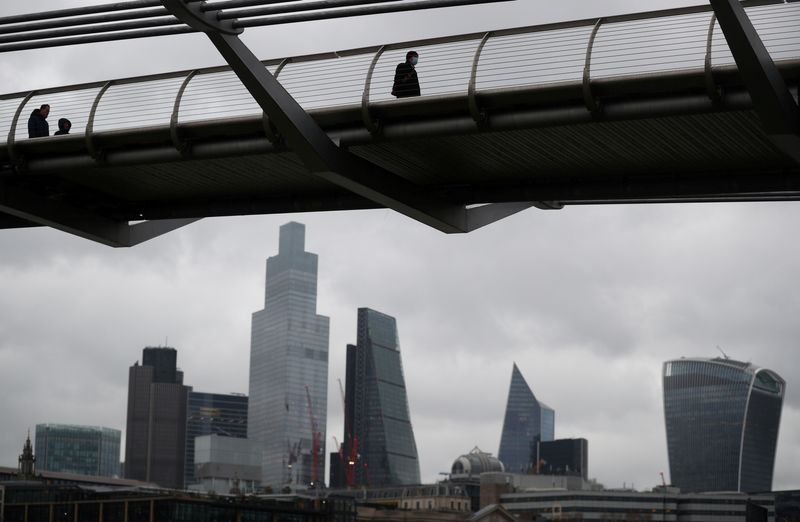 FILE PHOTO: People walk across Millennium Bridge with the City of London financial district seen behind, amid the coronavirus disease (COVID-19) pandemic, in London