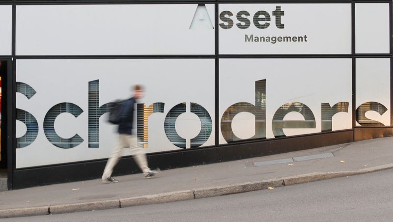 A man walks past the logo of investment management company Schroders in Zurich