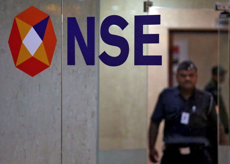 FILE PHOTO: FILE PHOTO: A security guard walks past the logo of the National Stock Exchange inside its building in Mumbai