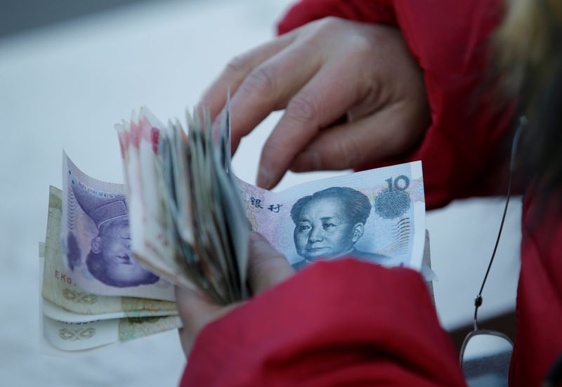 FILE PHOTO: A woman counts Chinese Yuan banknotes as she sells tickets for a job fair in Beijing