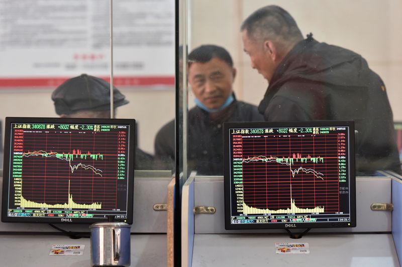 Investors are seen behind screens displaying stock information at a brokerage house in Fuyang