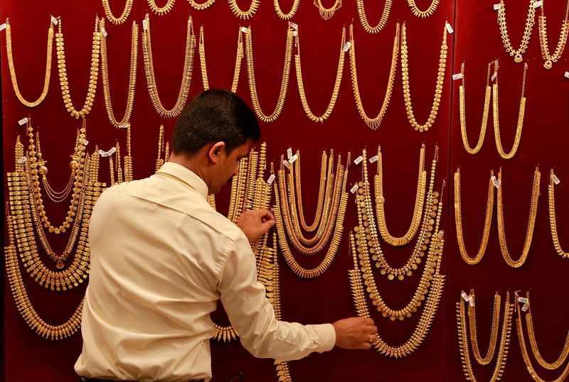 Salesman arranges gold ornaments on display board inside a jewellery showroom during Akshaya Tritiya, a major gold buying festival, in Kochi