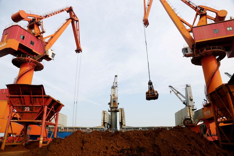 Cranes unload imported iron ore from a cargo vessel at a port in Lianyungang, Jiangsu