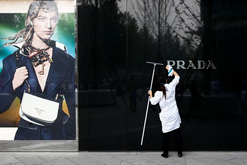 A woman cleans the brand logo at a Prada fashion boutique in Beijing