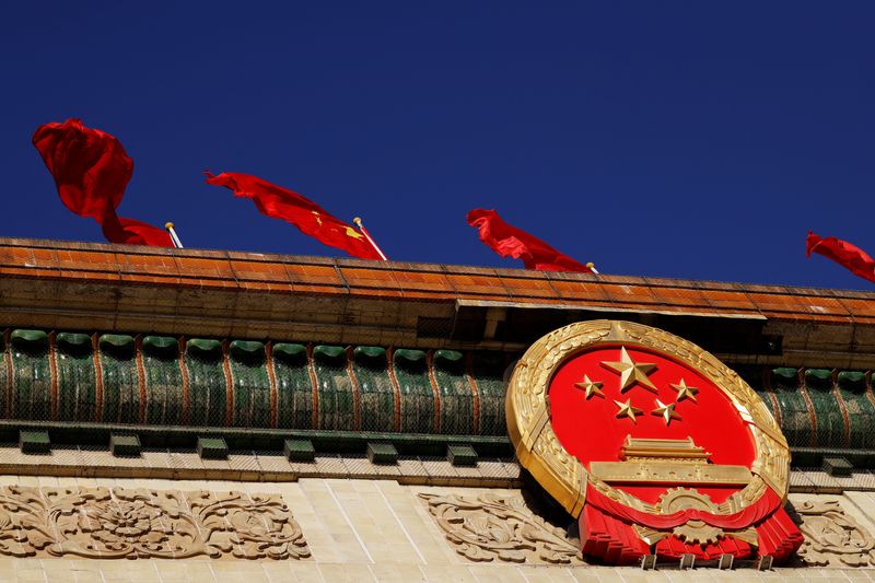 ARCHIV: Eine chinesische Flagge über dem nationalen Emblem in der Großen Halle des Volkes vor der Eröffnungssitzung des Nationalen Volkskongresses (NVK) in Peking, China, 5. März 2022. REUTERS/Carlos Garcia Rawlins