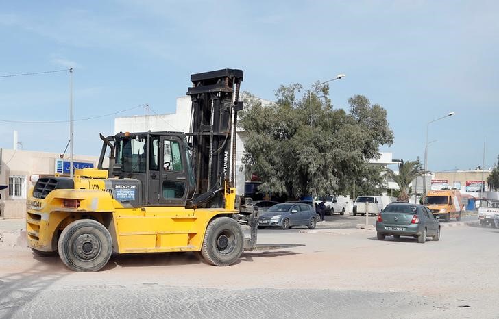 Vehicles and forklift are seen on road in Tunis