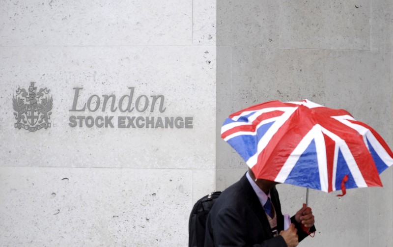 FILE PHOTO: A worker shelters from the rain as he passes the London Stock Exchange in London