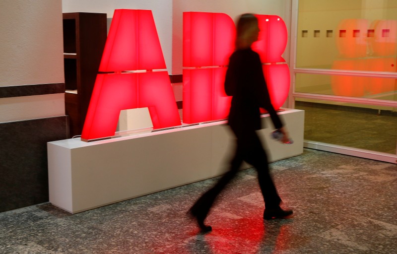 A woman walks past the logo of Swiss power technology and automation group ABB in Zurich