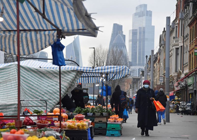 FILE PHOTO: People shop at market stalls, with skyscrapers of the CIty of London financial district seen behind, in London