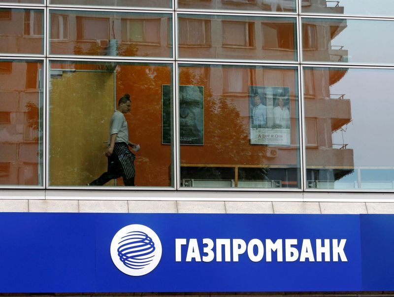 FILE PHOTO: A person is pictured through a window above a Gazprombank branch in Moscow