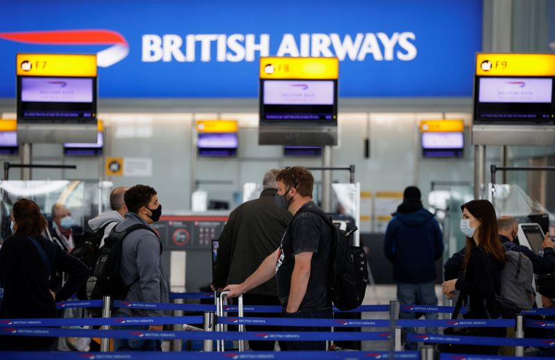 FILE PHOTO: Passengers stand in a queue to the British Airways check-in desks at Heathrow Airport