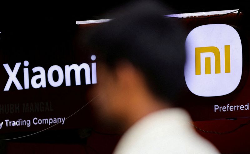 FILE PHOTO: A man walks past a logo of Xiaomi, a Chinese manufacturer of consumer electronics, outside a shop in Mumbai
