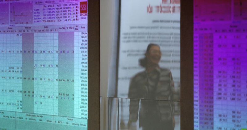 An investor is seen reflected on stock market screens at a securities company in Hanoi