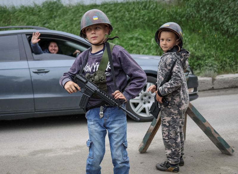 Ukrainian children play Ukrainian military near their houses in the village of Stoianka, in Kyiv region