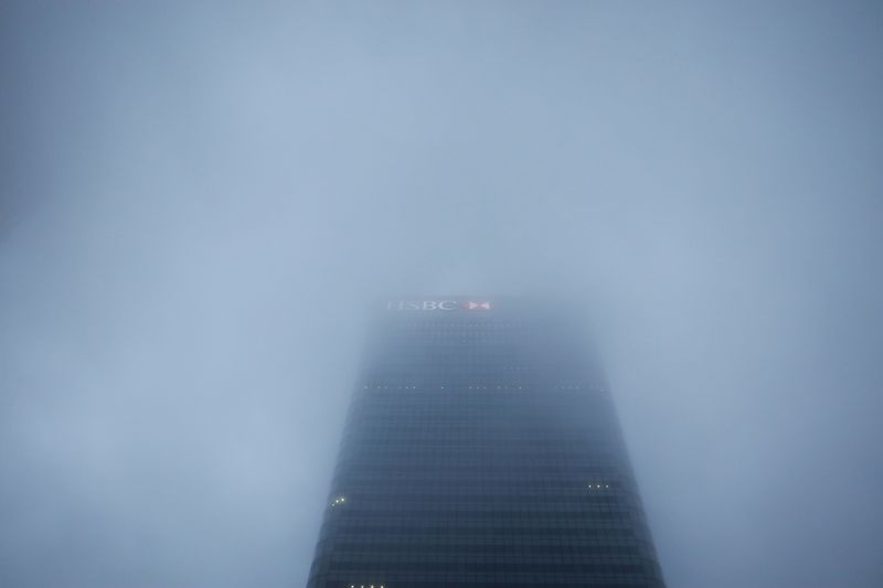 The logo on the building of HSBC's London headquarters appears through the early morning mist in London's Canary Wharf financial district