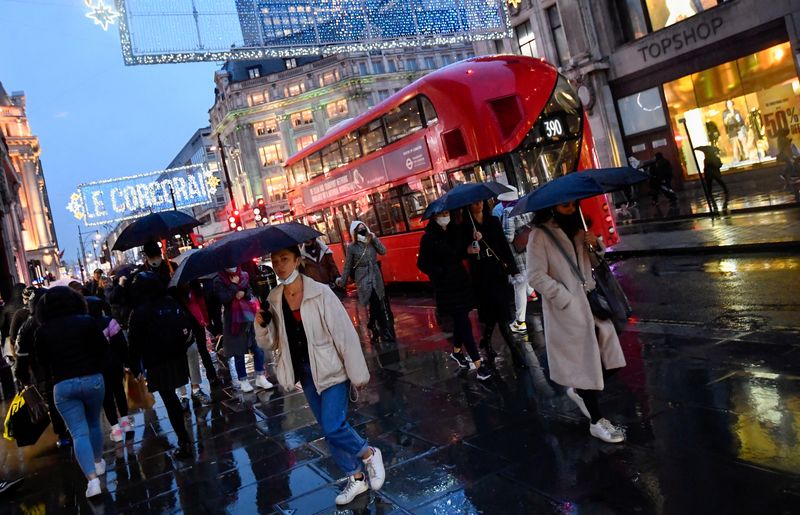 FILE PHOTO: Shoppers hold umbrellas as they walk, following the outbreak of the coronavirus disease (COVID-19), at Oxford Street in London