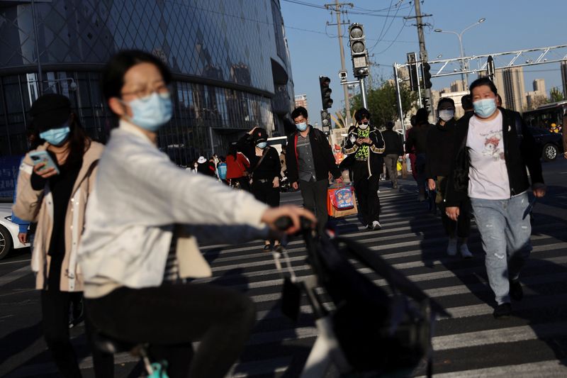 People wearing face masks to prevent the spread of the coronavirus disease (COVID-19) walk across a street near a shopping mall in Beijing