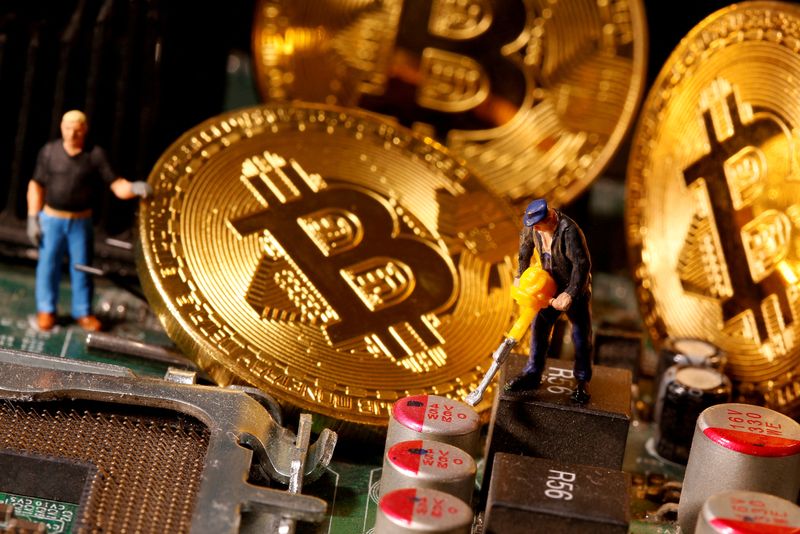 FILE PHOTO: A representation of virtual currency Bitcoin and small toy figures are placed on computer motherboard