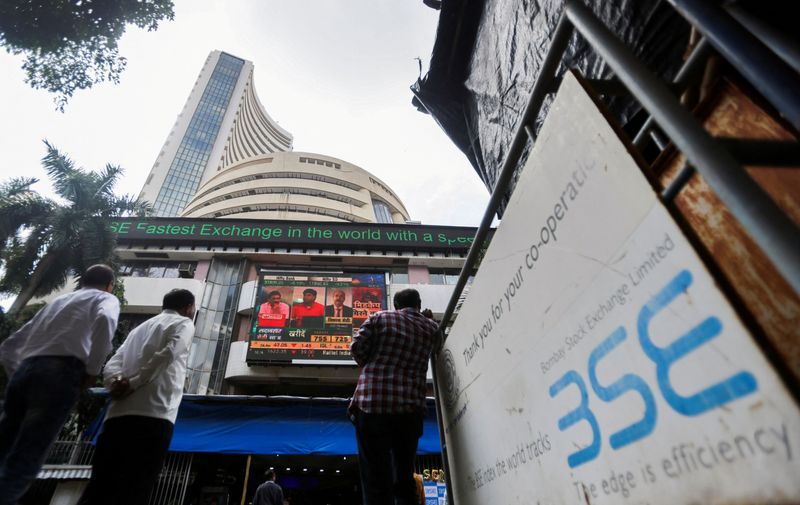 FILE PHOTO: People stand outside the Bombay Stock Exchange (BSE), after Sensex surpassed the 60,000 level for the first time, in Mumbai
