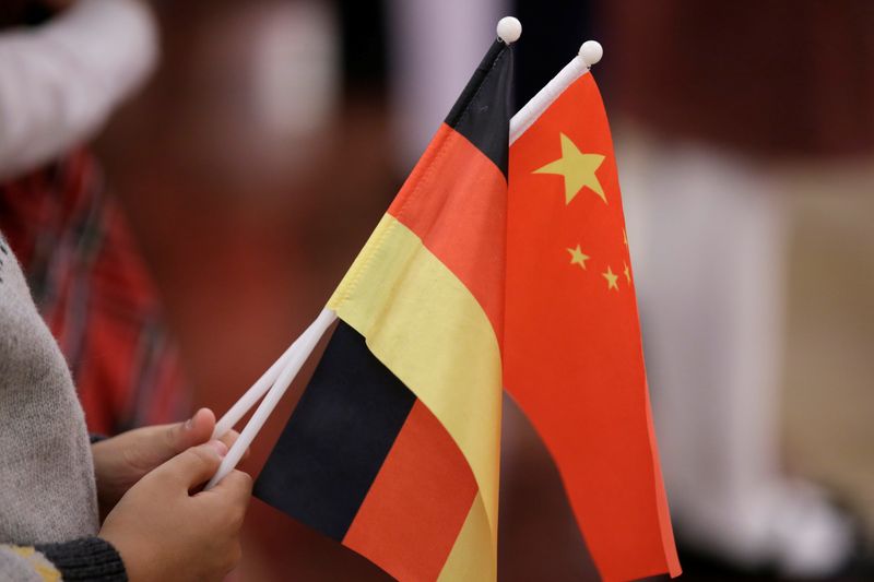 FILE PHOTO: A student holds flags of China and Germany before a welcome ceremony in Beijing