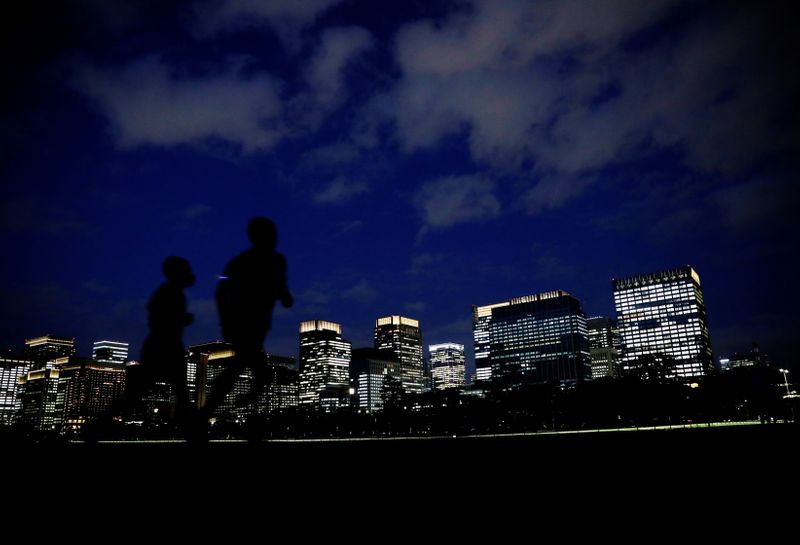 People run with Tokyo's business district in background, in Tokyo