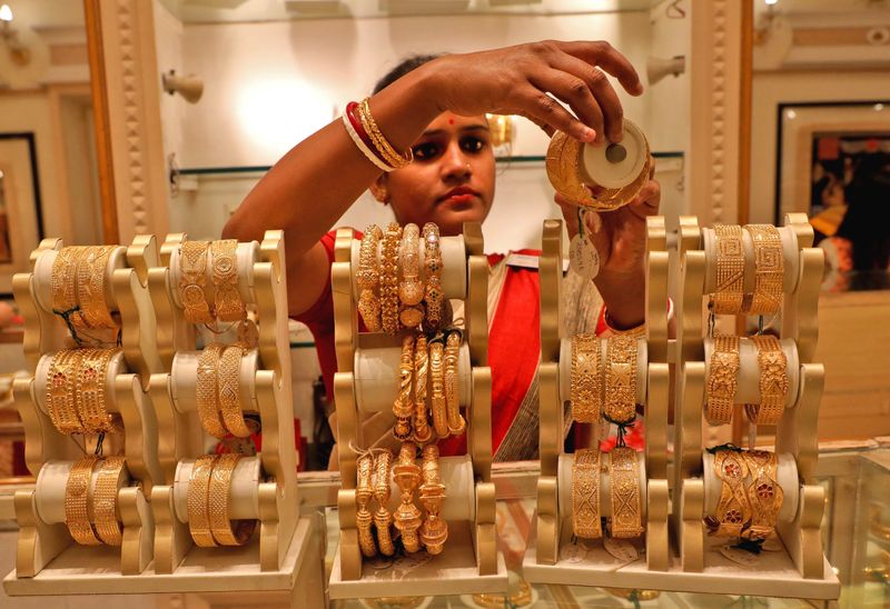 A saleswoman shows gold bangles to a customer at a jewellery showroom, in Kolkata