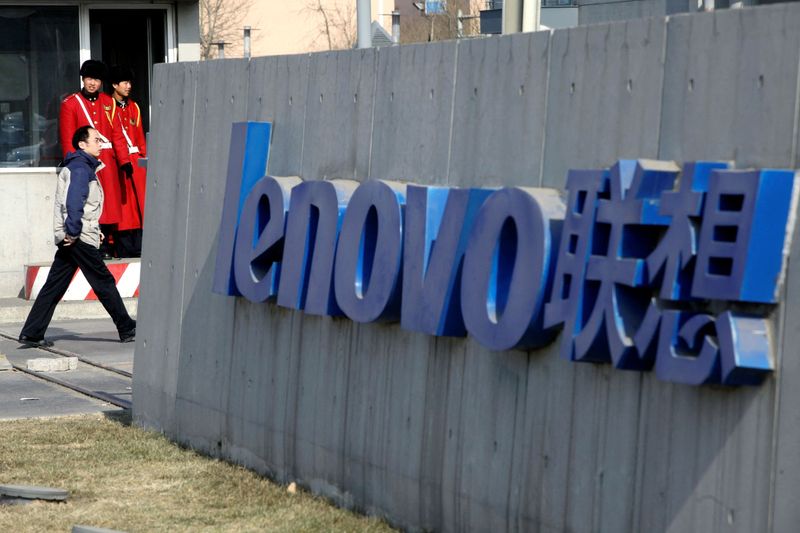 FILE PHOTO: A pedestrian walks past a Lenovo logo in Beijing
