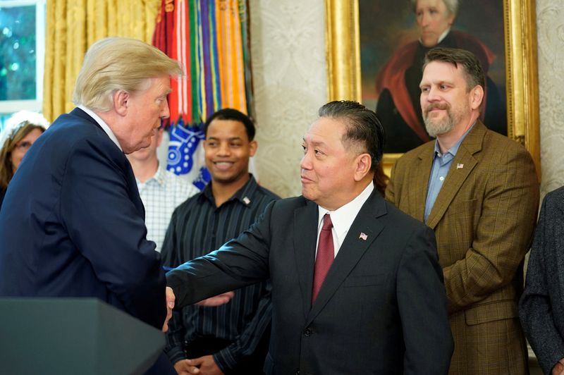 FILE PHOTO: Hock Tan, CEO of Broadcom, shakes hands with then U.S. President Donald Trump