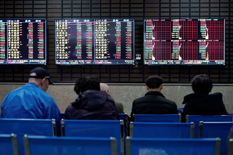 Investors look at screens showing stock information at a brokerage house in Shanghai