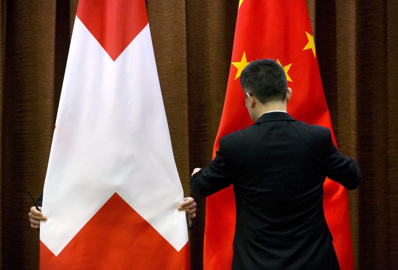 FILE PHOTO: Workers adjust a Swiss and Chinese flag before a bilateral meeting between Chinese Foreign Minister Wang Yi and Swiss Foreign Minister Didier Burkhalter at the Ministry of Foreign Affairs in Beijing