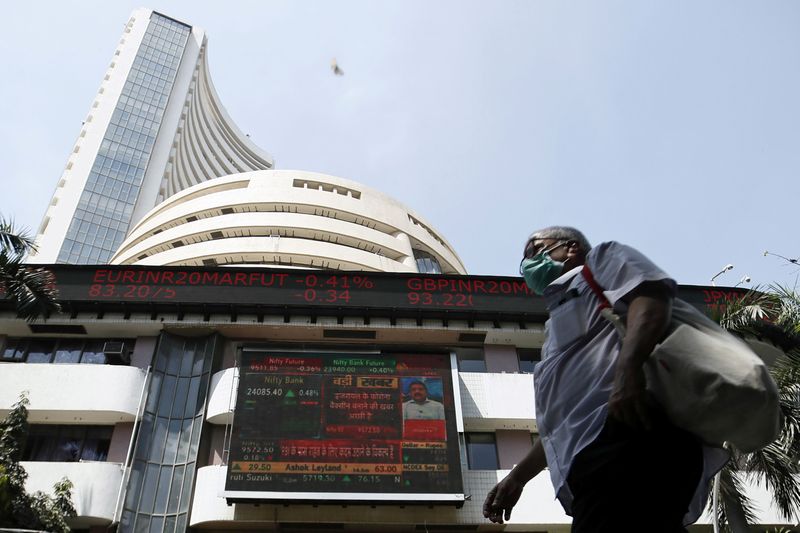 FILE PHOTO: A man wearing a protective mask walks past the Bombay Stock Exchange (BSE) building in Mumbai