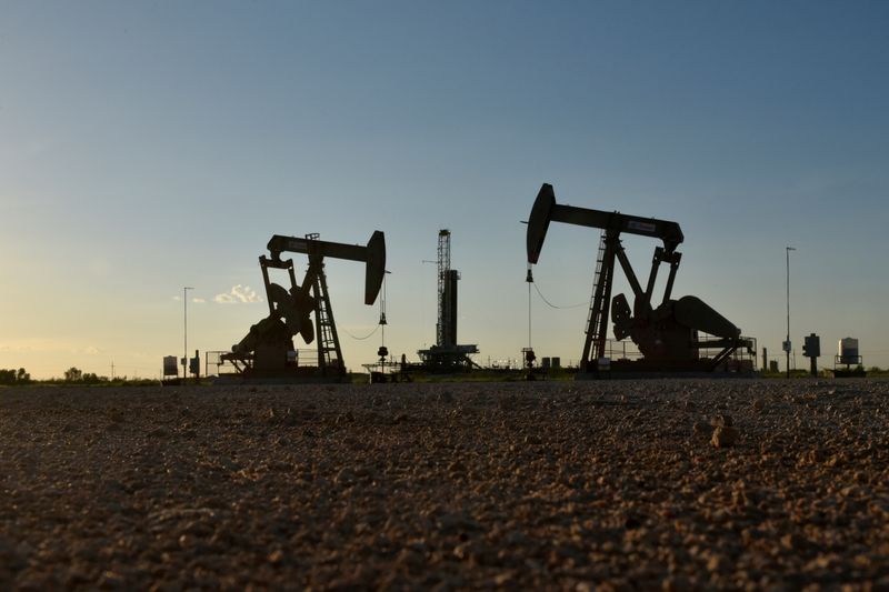 Imagen de archivo de balancines petroleros operando frente a una plataforma de perforación en un campo petrolero en Midland