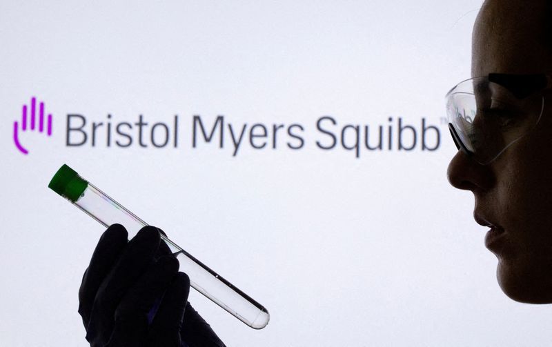 FILE PHOTO: A woman holds test tube in front of displayed Bristol Myers Squibb logo in this illustration