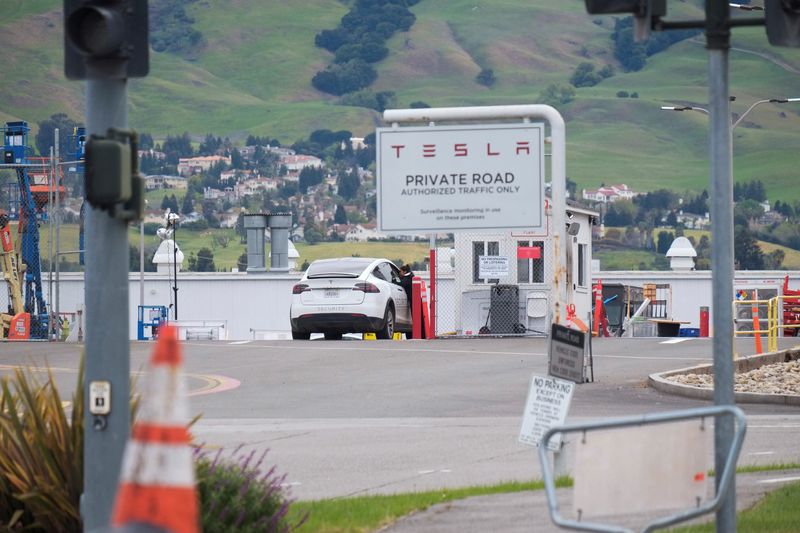 FILE PHOTO: An employee of a Tesla Inc's U.S. vehicle factory is seen at a security gate in Fremont, California