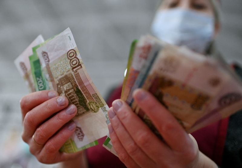 FILE PHOTO: A vendor counts Russian rouble banknotes at a market in Omsk