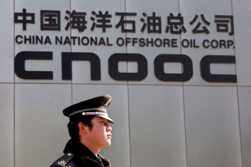 FILE PHOTO: A security officer keeps watch outside the headquarters of CNOOC in Beijing